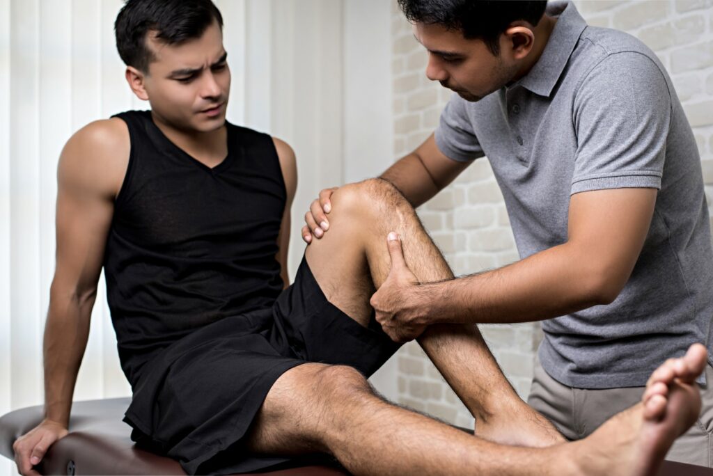 An athletic trainer works with an athlete who has injured his knee. 