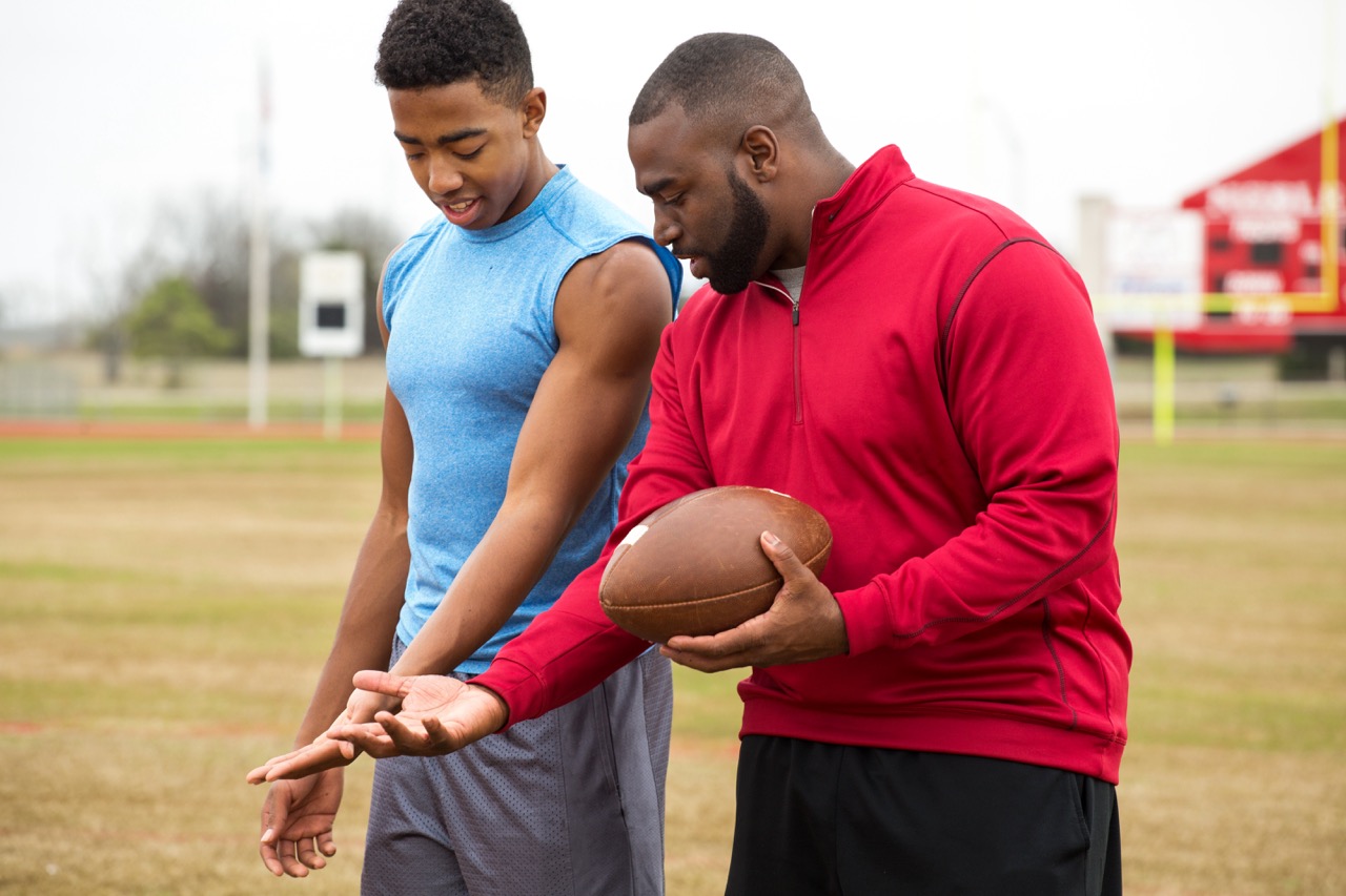 Athletic trainer examines a college quarterback’s arm injury.
