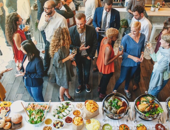 A group of people stands in front of a table of refreshments at an event.