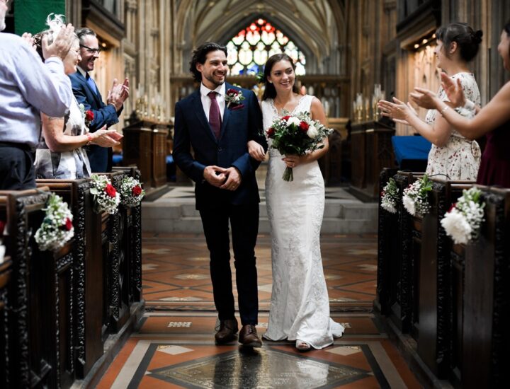 A newly married bride and groom walk down the church aisle together after their marriage ceremony.
