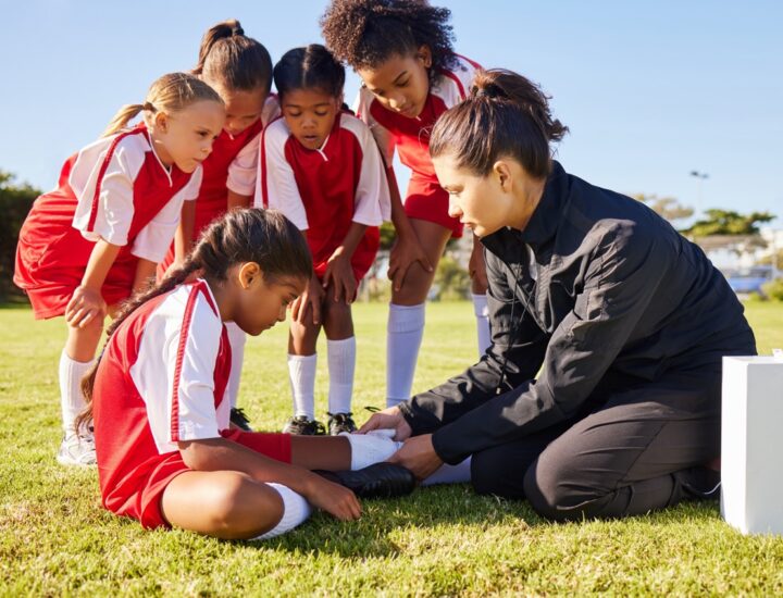 Youth athlete receiving first aid at sports camp, underscoring the need for liability coverage.