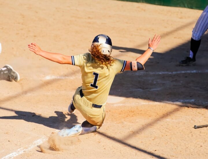 A softball player slides into home plate, and her school is ready with student-athlete insurance solutions if an injury should occur.